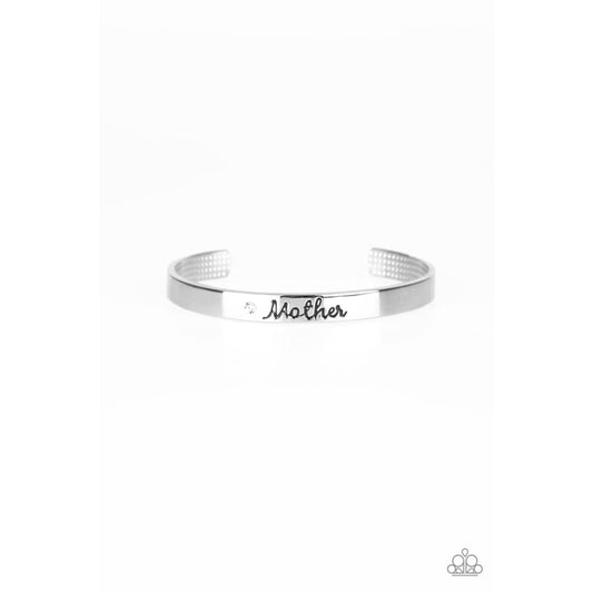 Paparazzi Every Day Is Mothers Day - Mom Bracelet Silver A sleek silver cuff wraps around the wrist in a casual fashion. Dotted with a dainty white rhinestone, the shimmery cuff is engraved in the word “Mother” for a loving finish. Sold as one individual cuff bracelet.