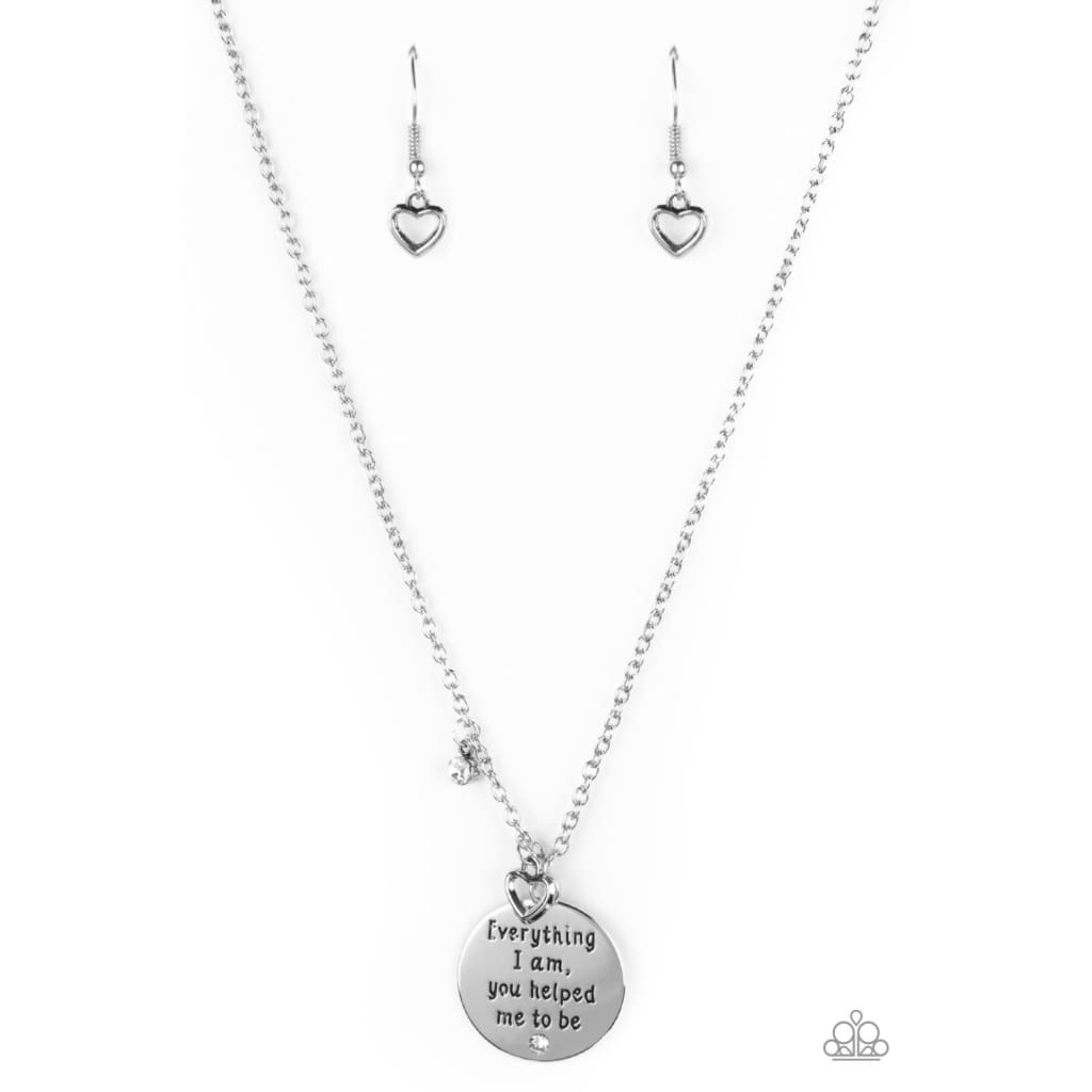 Paparazzi Everything I Am - White Pendant Necklace White rhinestone, silver heart, and a silver disc with the inspirational phrase, "Everything I am, you helped me to be", swings below the collar. Sold as one individual white pendant necklace. Includes one pair of matching earrings. Free shipping on orders over $75