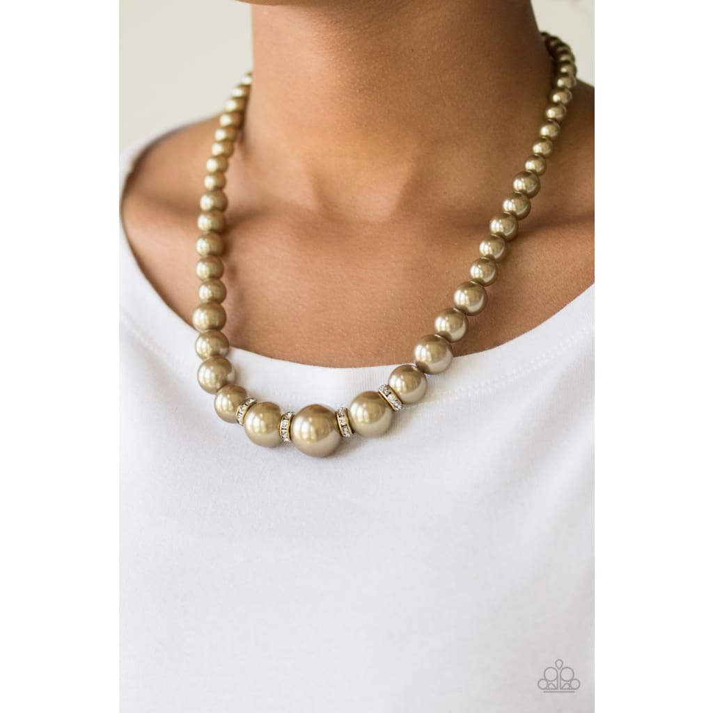 Paparazzi Party Pearls - Brass Necklace Pearly brass beads trickle below the collar for a classic look. Dazzling white rhinestones, glittery rings are sprinkled between the pearly beads for a timeless finish. Sold as one individual brass necklace. Includes one pair of matching earrings.
